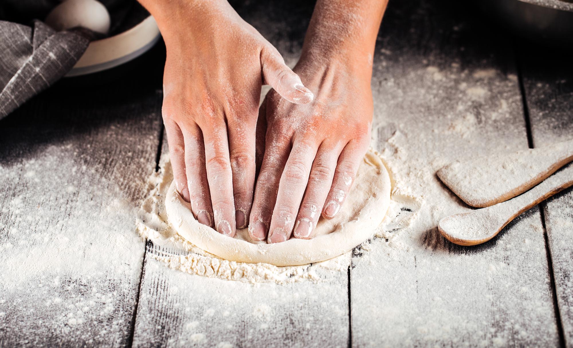 Chef che impasta a mano su tavolo di legno